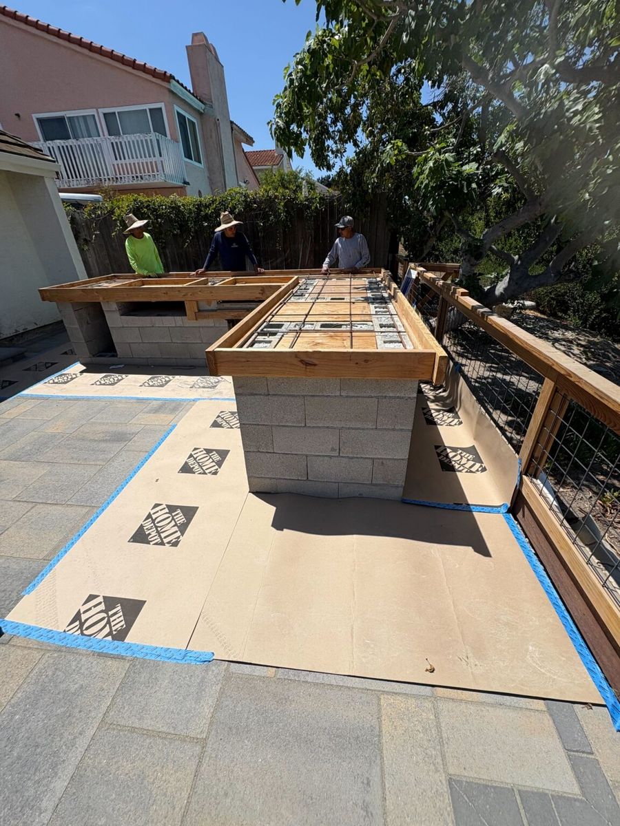 An Install-It-Direct crew framing an outdoor kitchen on a paver patio